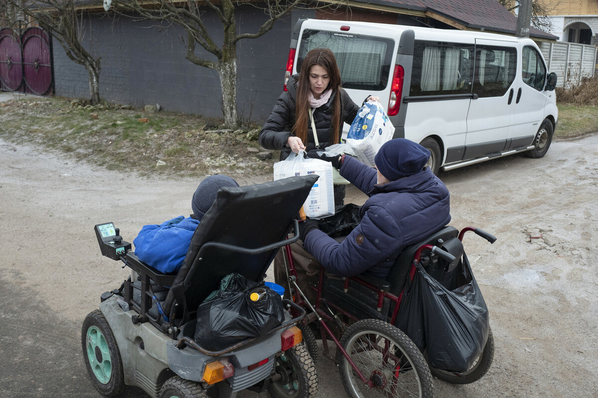 Ana Kyleva verteilt Hygienekits an zwei Menschen im Rollstuhl.