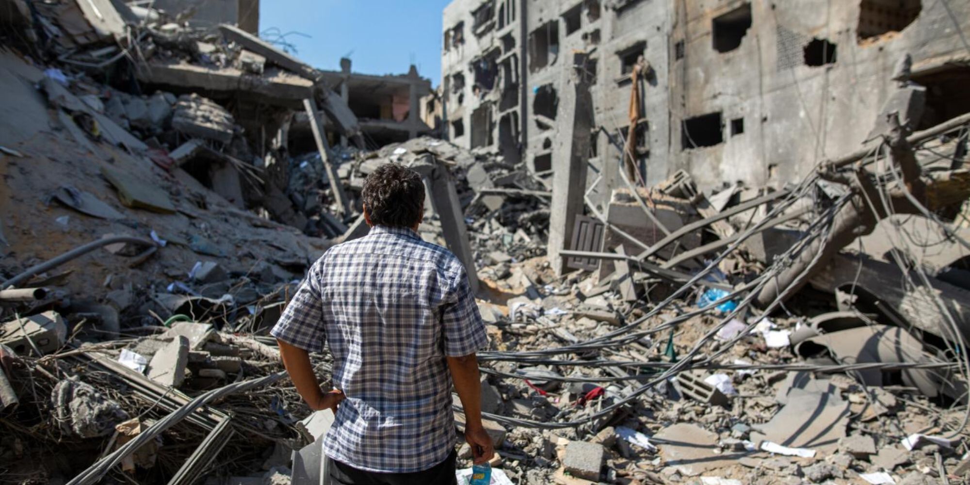 Ein Mann schaut auf ein zerstörtes Gebäude in Gaza.